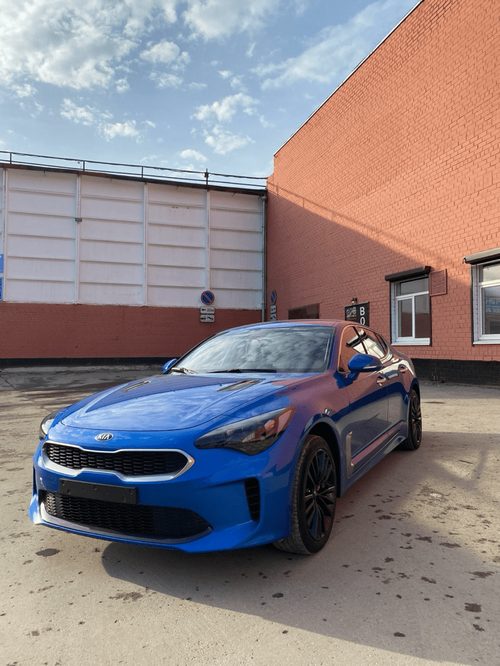 Синий Kia Stinger после полировки у бокса студии
